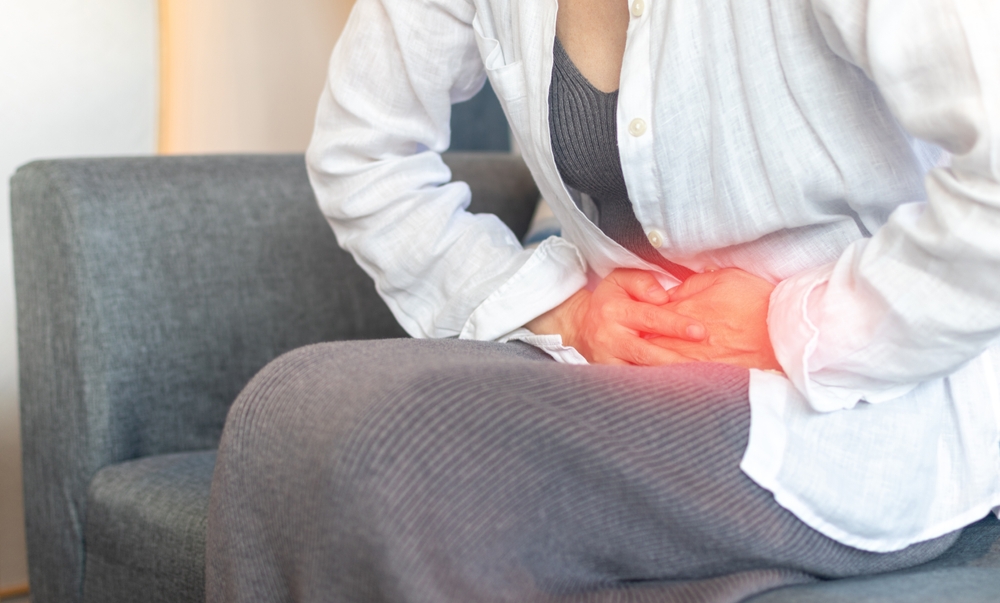 Woman sitting down holding her stomach in pelvic pain